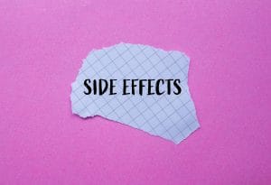 tort piece of grey paper with side effects in black on pink background
