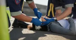 Paramedic, emergency and hands on head injury on road in car crash accident with healthcare help. EMS, wrapping bandage and first responder with victim or rescue in street to save person outdoors