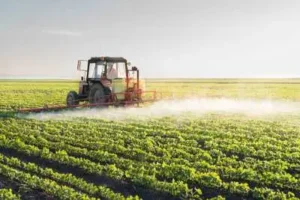 Tractor spraying paraquat on soybean field