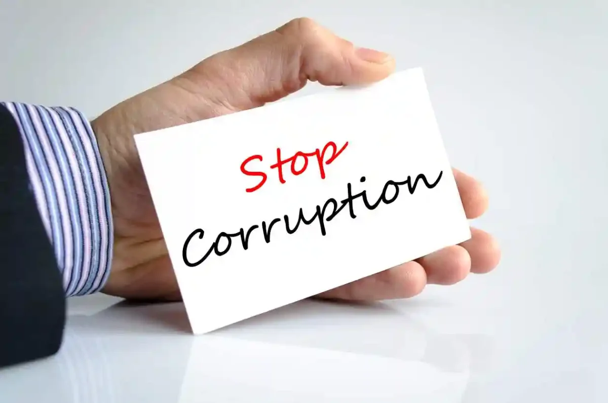 mans hand holding white cared with stop corruption in red and black used in Causes of Accounting Frauds