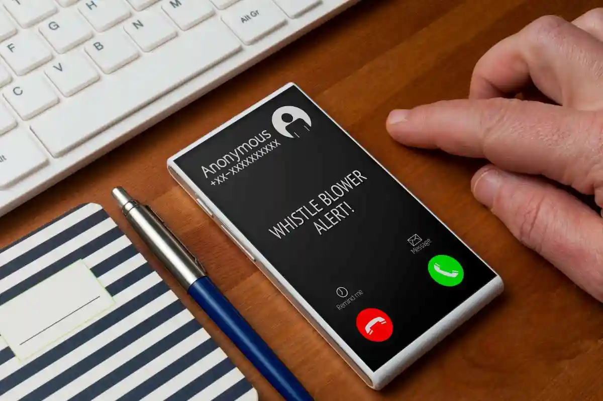Whistleblowing concept: white smartphone on wooden table show a whistle blower alert on an anonymous call used in Whistleblower Protections in Financial Reporting 


