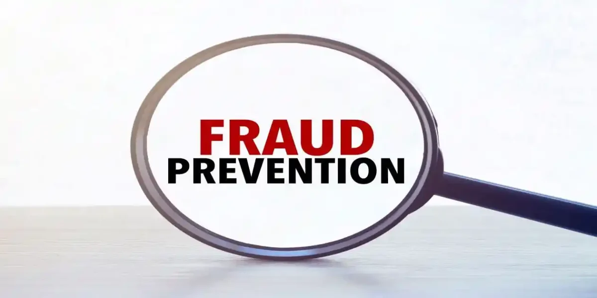 Magnifying glass with text fraud prevention on wooden table. Used in Asset Misappropriation Red Flags
