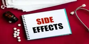 side effects in red and blackk on red table next to a stethoscope used in Dupixent and Cancer,