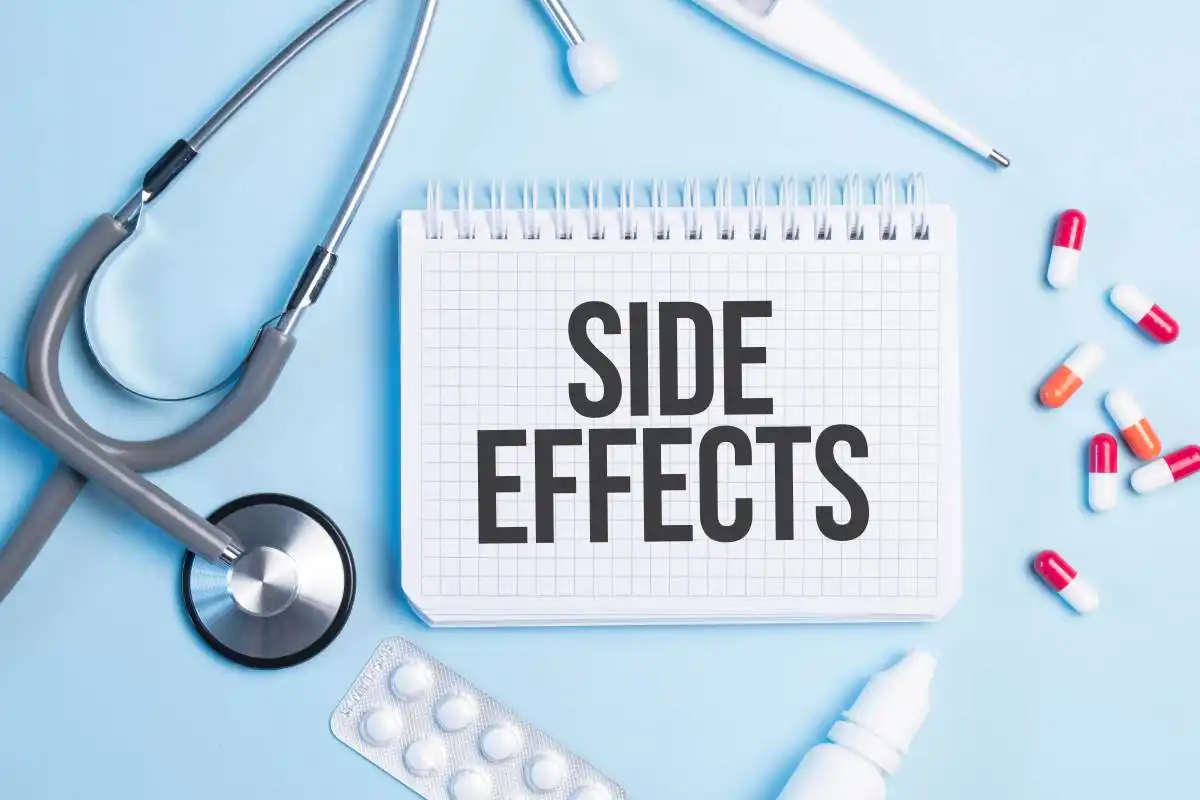 The word SIDE EFFECTS written on a white notepad on a blue background near a stethoscope, syringe, electronic thermometer and pills. Medical concept used in Dupixent Lawsuit