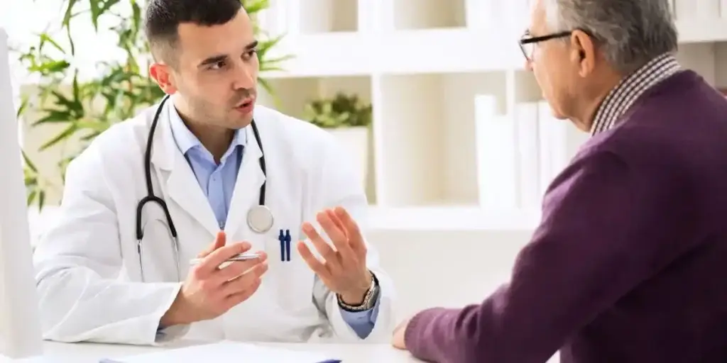 Mounjaro Lawsuit Update feature pic of doctor in white coat meeting at table with male patient in red sweater, wearing glasses.