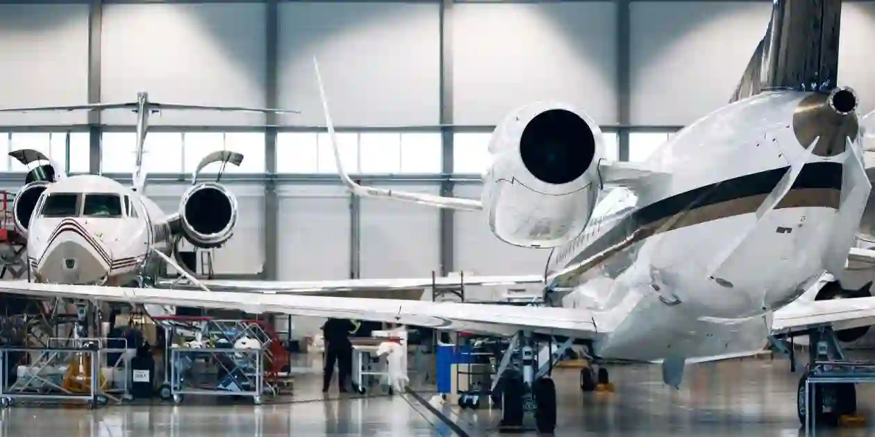 Maintenance of airplane in large white hangar. Modern private jet at the factory used in Symptoms of Aerotoxic Syndrome