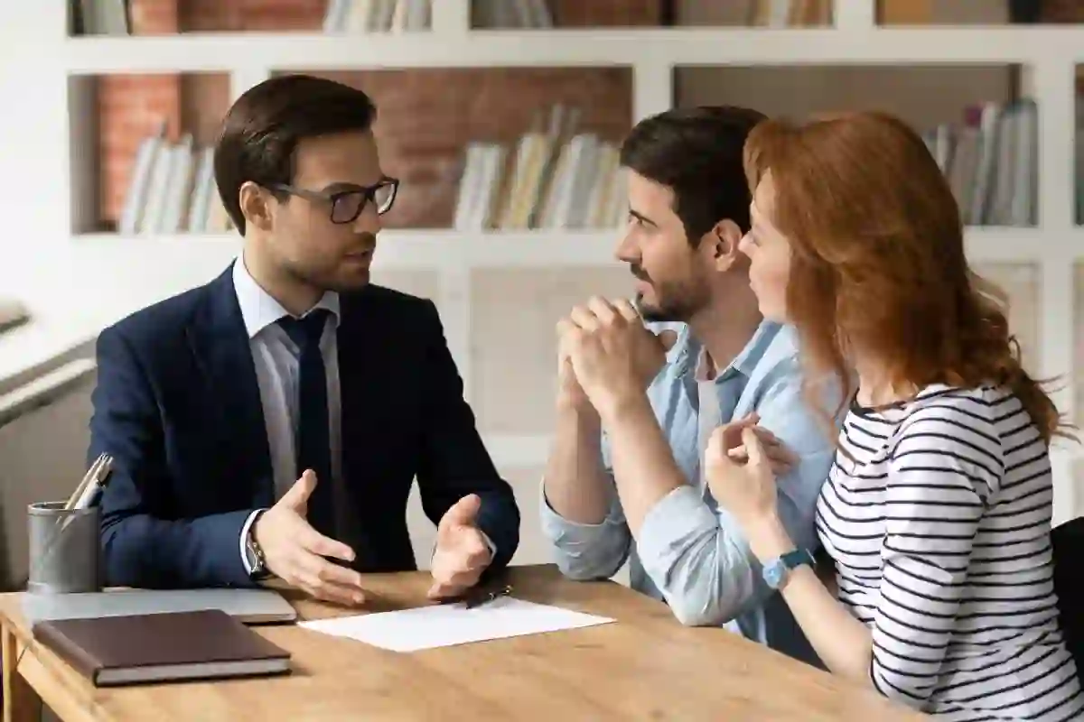Professional male lawyer financial advisor consulting happy family couple clients in modern office. Interested young customers meeting realtor broker bank worker, discussing agreement or deal. used in GM Transmission Lawyer

