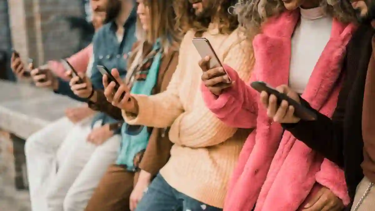 Group of young multi-ethnic people using smartphone sitting in a bench. Multiracial people holding smart mobile phones and watching their screen outdoors.
used in Social Media Addiction Lawsuit