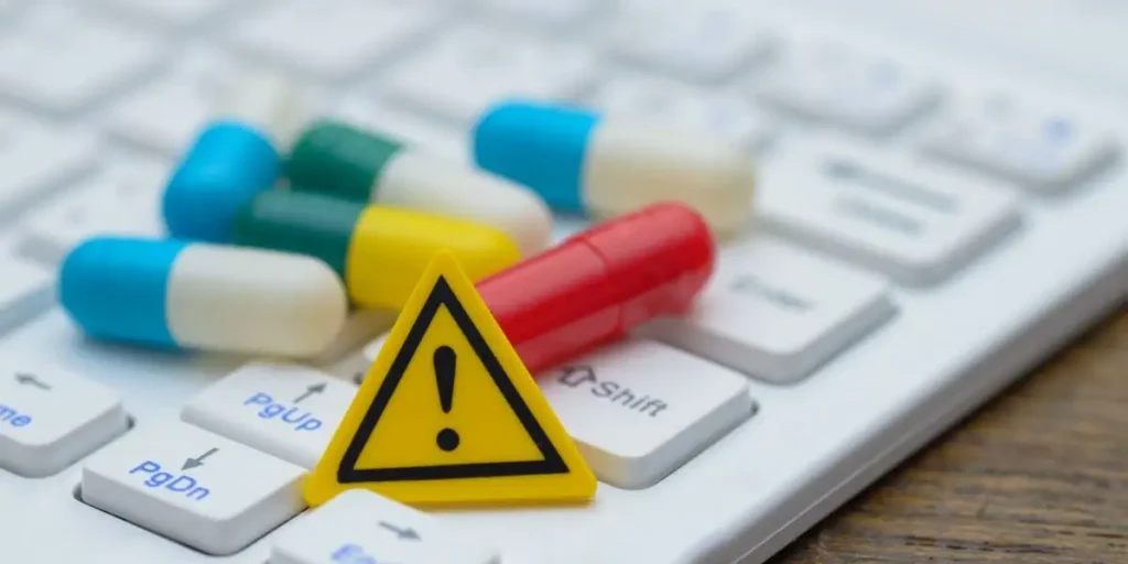 An exclamation mark sign and a pile of pills on a computer keyboard, representing the potential hazards of online drug information. used in Ocaliva Lawsuit Injury Lawyer in Tennessee